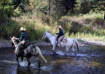 Twin Wranglers riding across the Fisher River